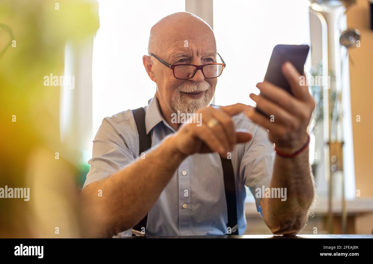 Prise de vue d'un homme âgé utilisant un téléphone portable à accueil Banque D'Images