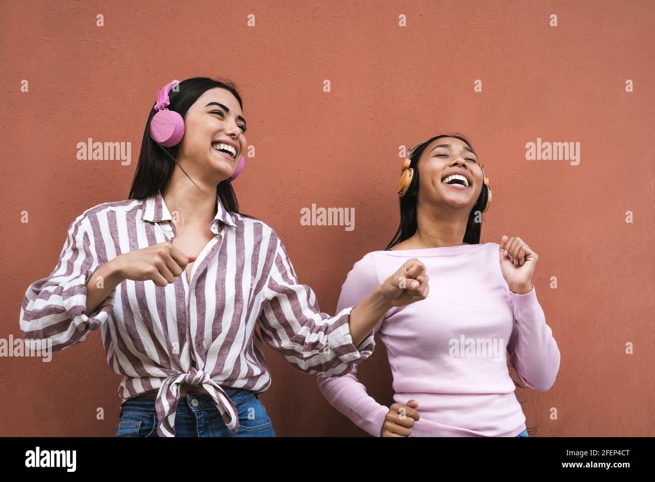 Jeunes femmes latines heureuses qui dansent et écoutent de la musique avec casque sans fil Banque D'Images