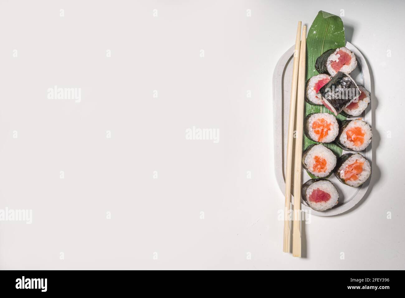 Petits pains à sushi, riz et poisson, sauce soja sur fond blanc Banque D'Images