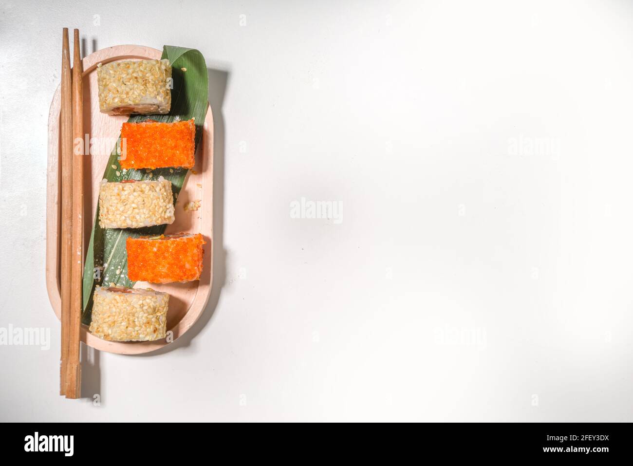 Petits pains à sushi, riz et poisson, sauce soja sur fond blanc Banque D'Images