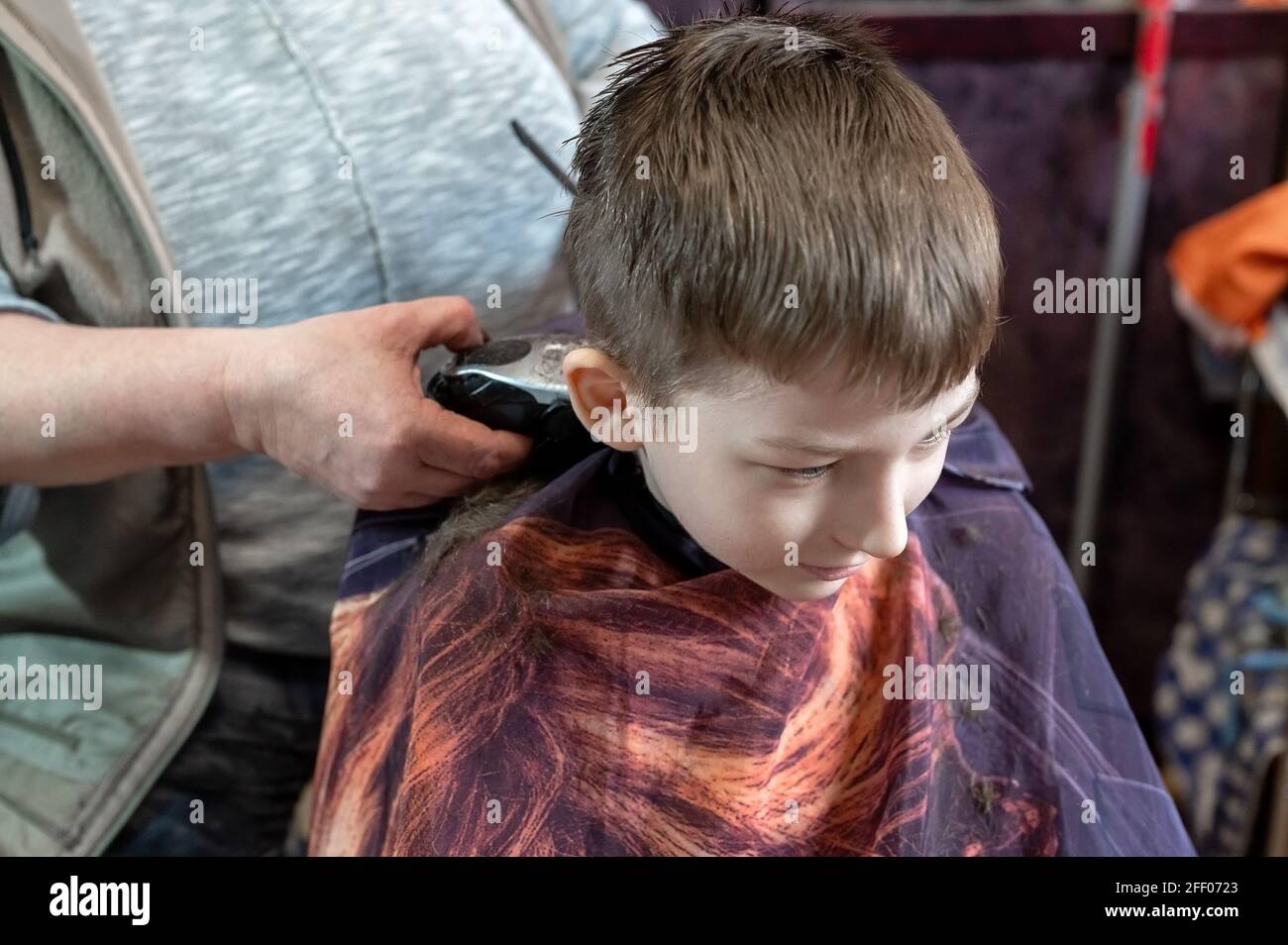 Coupe de cheveux pour petit garçon à la maison par maintien Banque D'Images