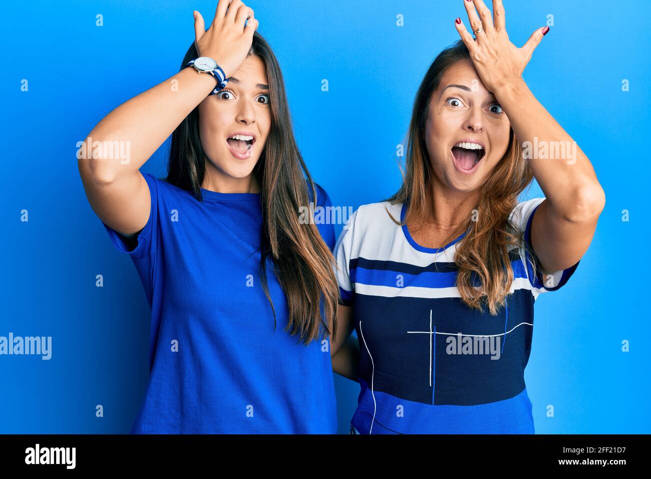 Famille hispanique de la mère et de la fille portant des vêtements décontractés sur fond bleu surpris avec la main sur la tête pour l'erreur, rappelez-vous erreur. oublié, ba Banque D'Images Famille hispanique de la mère et de la fille portant des vêtements décontractés sur fond bleu surpris avec la main sur la tête pour l'erreur, rappelez-vous erreur. oublié, ba Banque D'Images