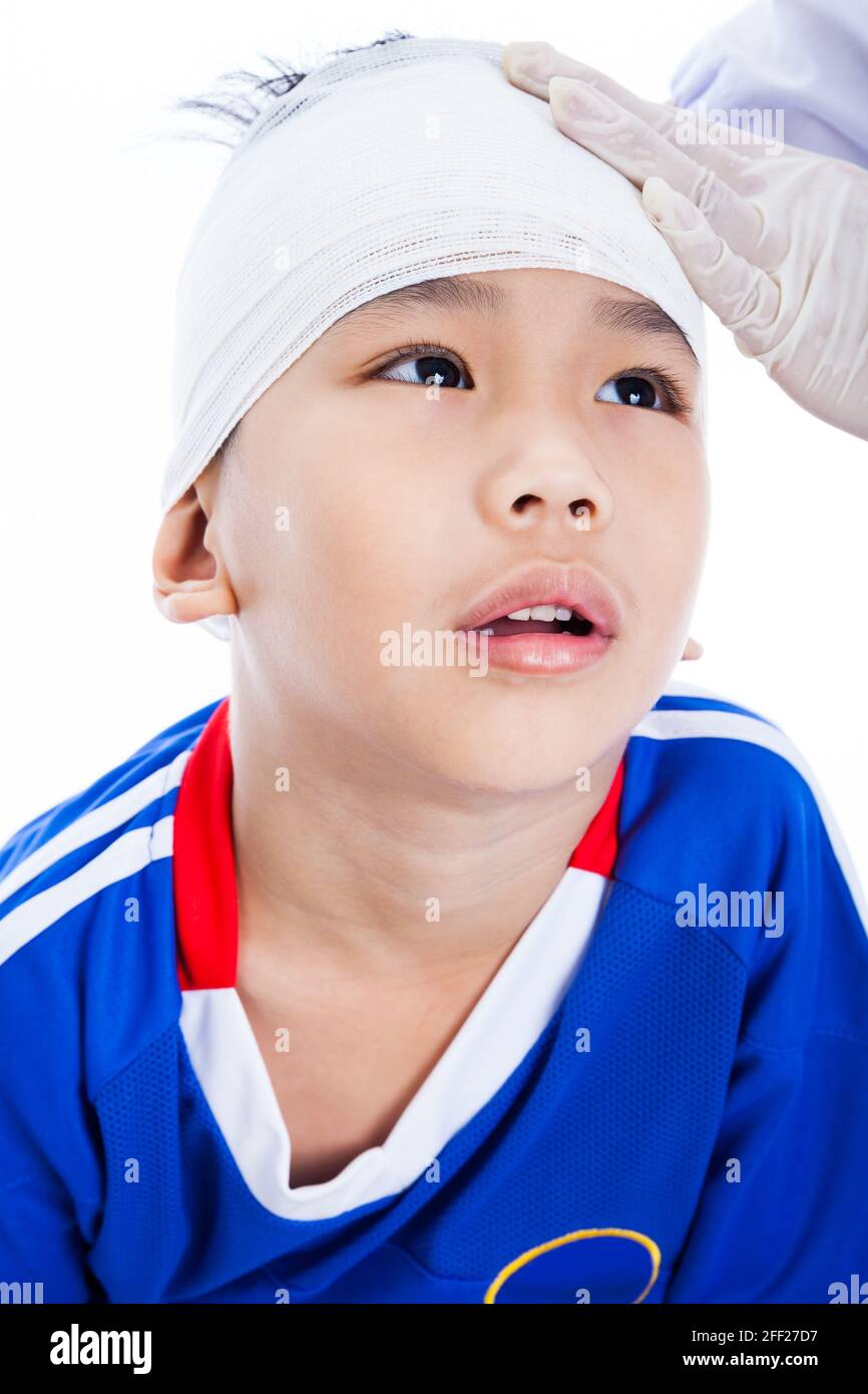 Athlète petit asiatique (thaïlandais) garçon en bleu sportswear avec traumatisme de la tête. Le médecin fait un bandage sur le patient de tête. Enfant malheureux, sur fond blanc Banque D'Images