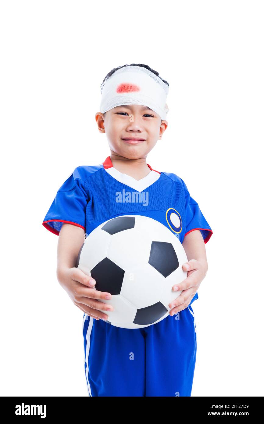 Athlète petit asiatique (thaïlandais) garçon en bleu sportswear avec traumatisme de la tête tenant un football et pleurant, sanglant sur le bandage, tirer en studio, isolé Banque D'Images