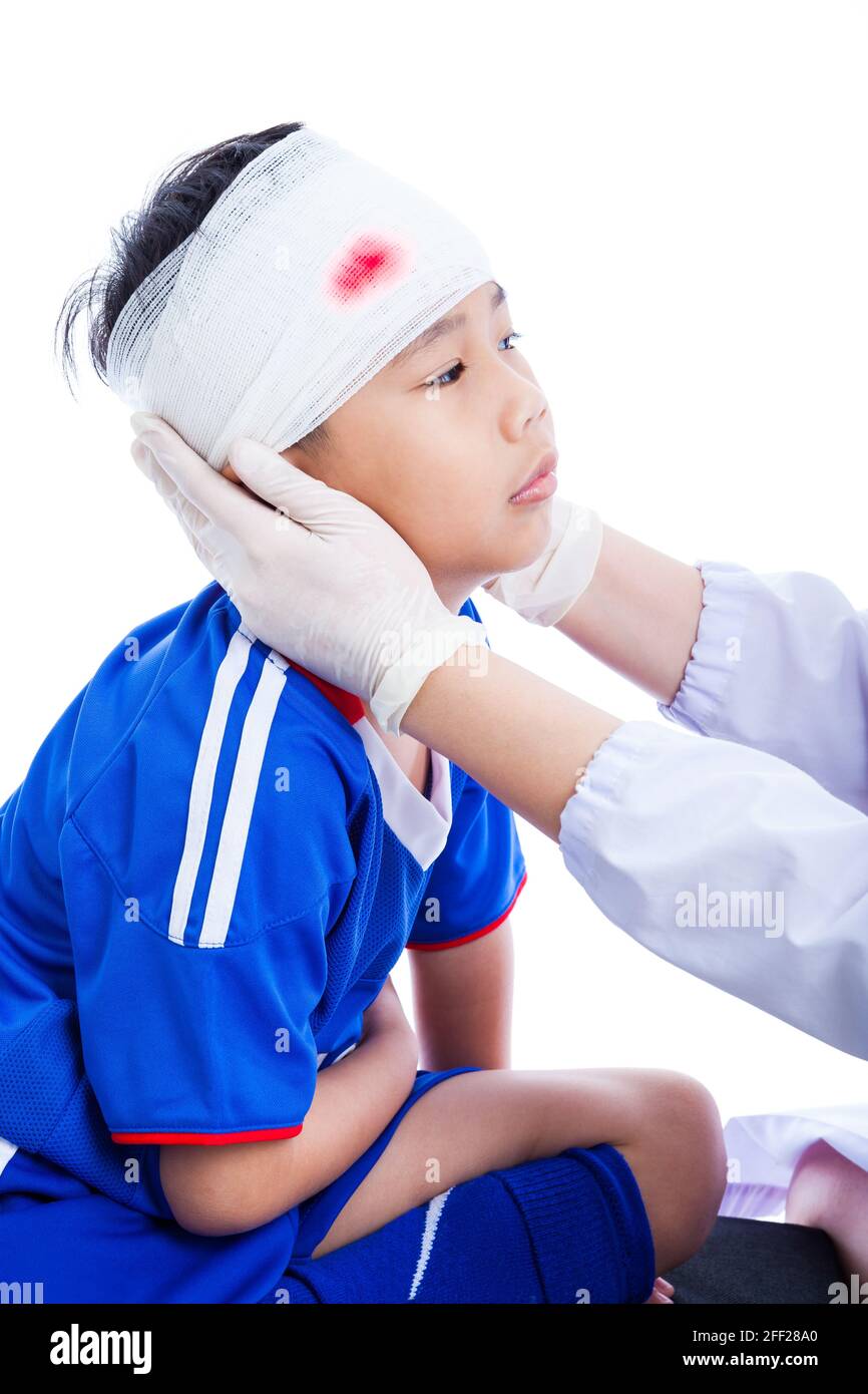 Blessures sportives. Athlète petit asiatique (thaïlandais) garçon en bleu sportswear avec traumatisme de la tête, sanglant sur le bandage. Le médecin fait un bandage sur le patient de tête, Banque D'Images