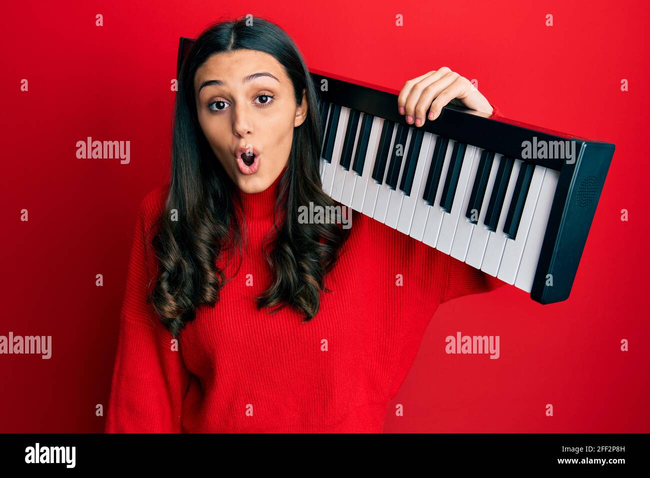 Jeune femme hispanique tenant clavier de piano peur et stupéfait avec la  bouche ouverte pour la surprise, incrédulité visage Photo Stock - Alamy