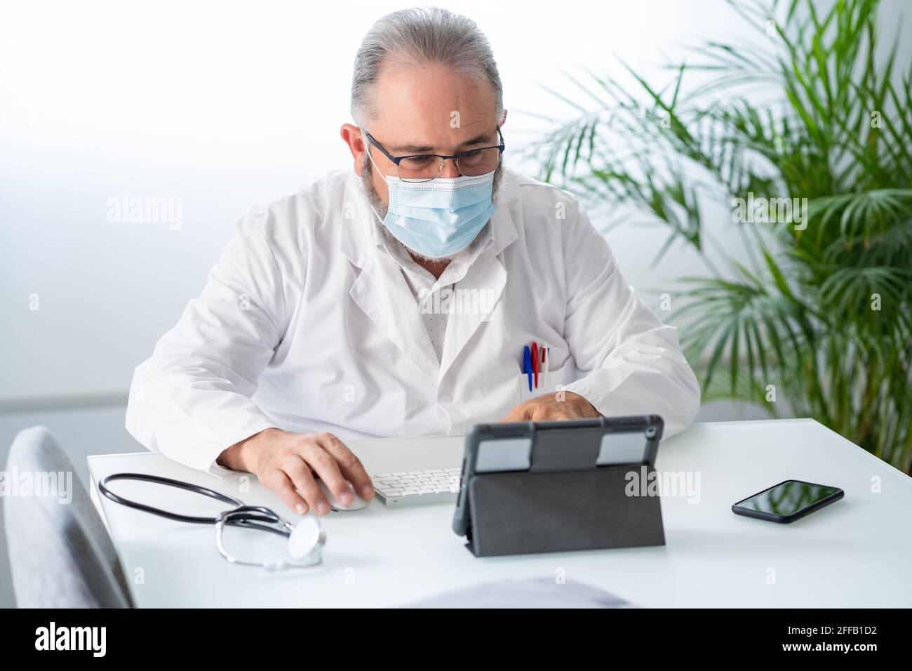 Médecin ayant une vidéoconférence avec tablette dans son bureau Banque D'Images