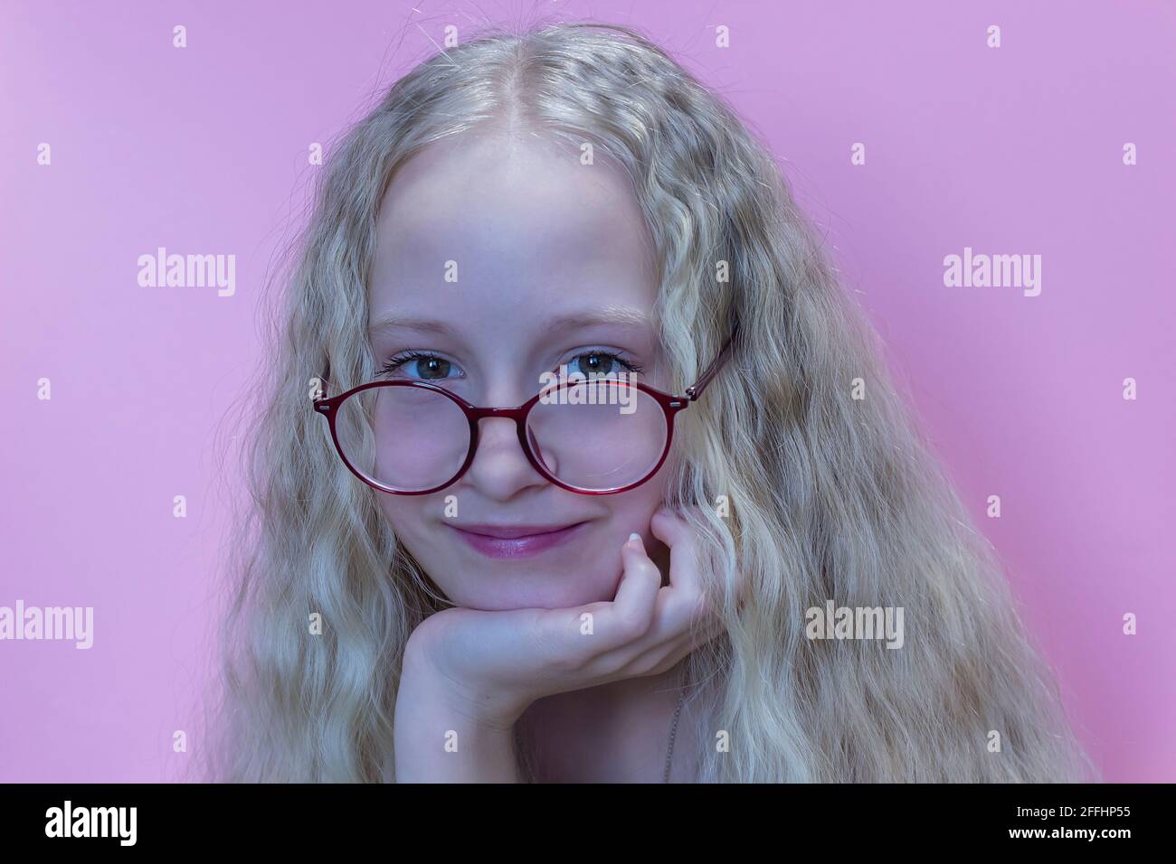 Portrait d'une belle adolescente en lunettes rouges avec cheveux blonds tourbillonnants Banque D'Images