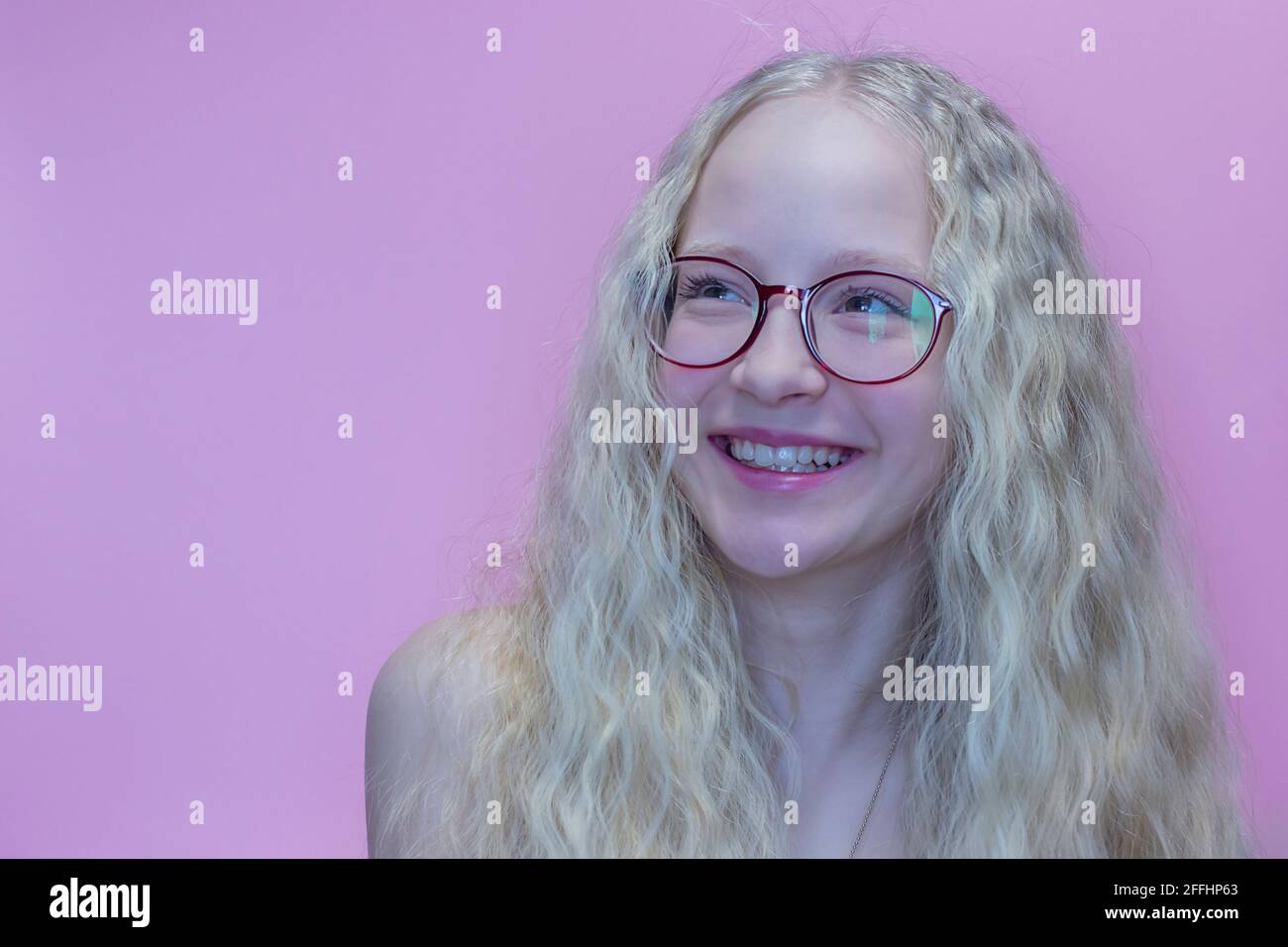 Portrait d'une belle adolescente en lunettes rouges avec cheveux blonds tourbillonnants Banque D'Images