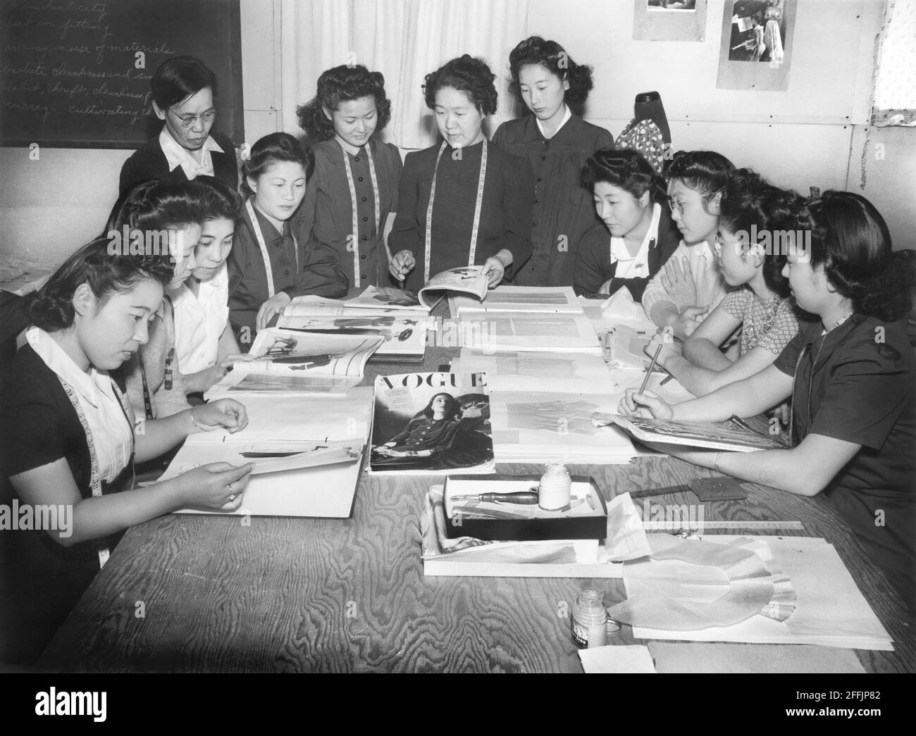 Mme Ryie Yoshizawa, enseignante de mode et de design, avec un groupe d'étudiants qui s'intéressent aux magazines et aux modèles de mode, Manzanar Relocation Center, Californie, Etats-Unis, Ansel Adams, Collection Manzanar War Relocation Centre, 1943 Banque D'Images