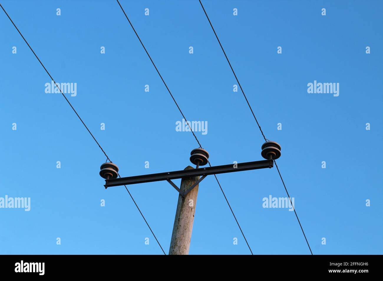 Gros plan du poteau de service public soutenant la ligne électrique sur toile de fond du ciel bleu clair Banque D'Images