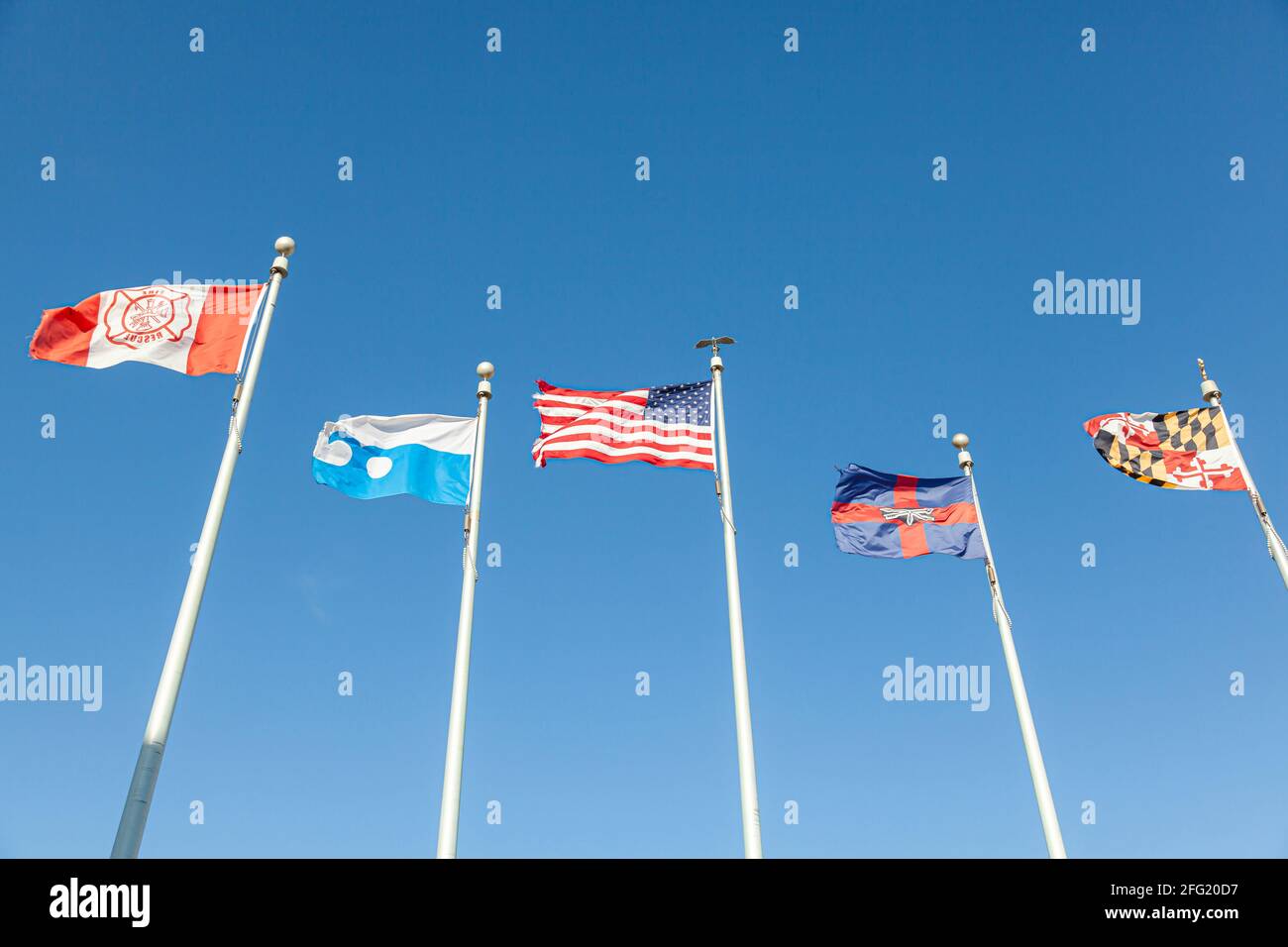 Cinq drapeaux agitant lors d'une journée venteuse à Ocean City Beach. Ils représentent Fire and Rescue, Ocean City, Maryland, États-Unis, le comté de Worcester et l'État de Mar Banque D'Images