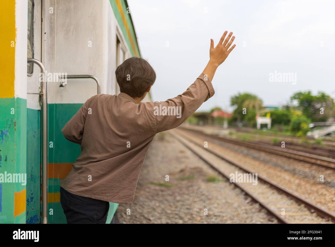 Beau jeune homme asiatique main pour dire bonjour ou Au revoir à un ami en train, en agitant Au revoir Banque D'Images