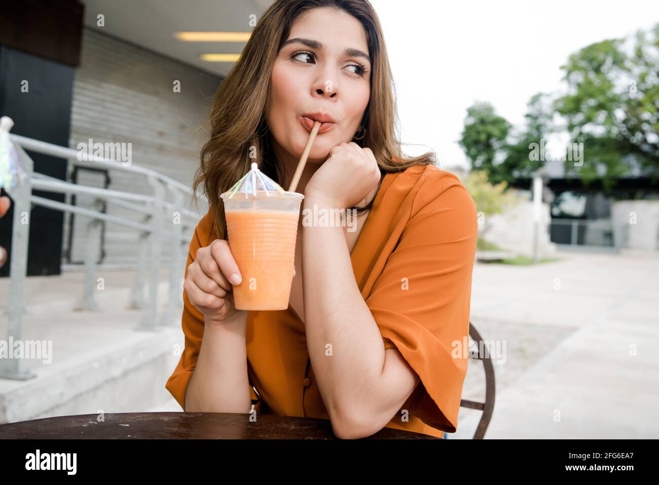 Femme qui boit du jus de fruits frais à l'extérieur. Banque D'Images