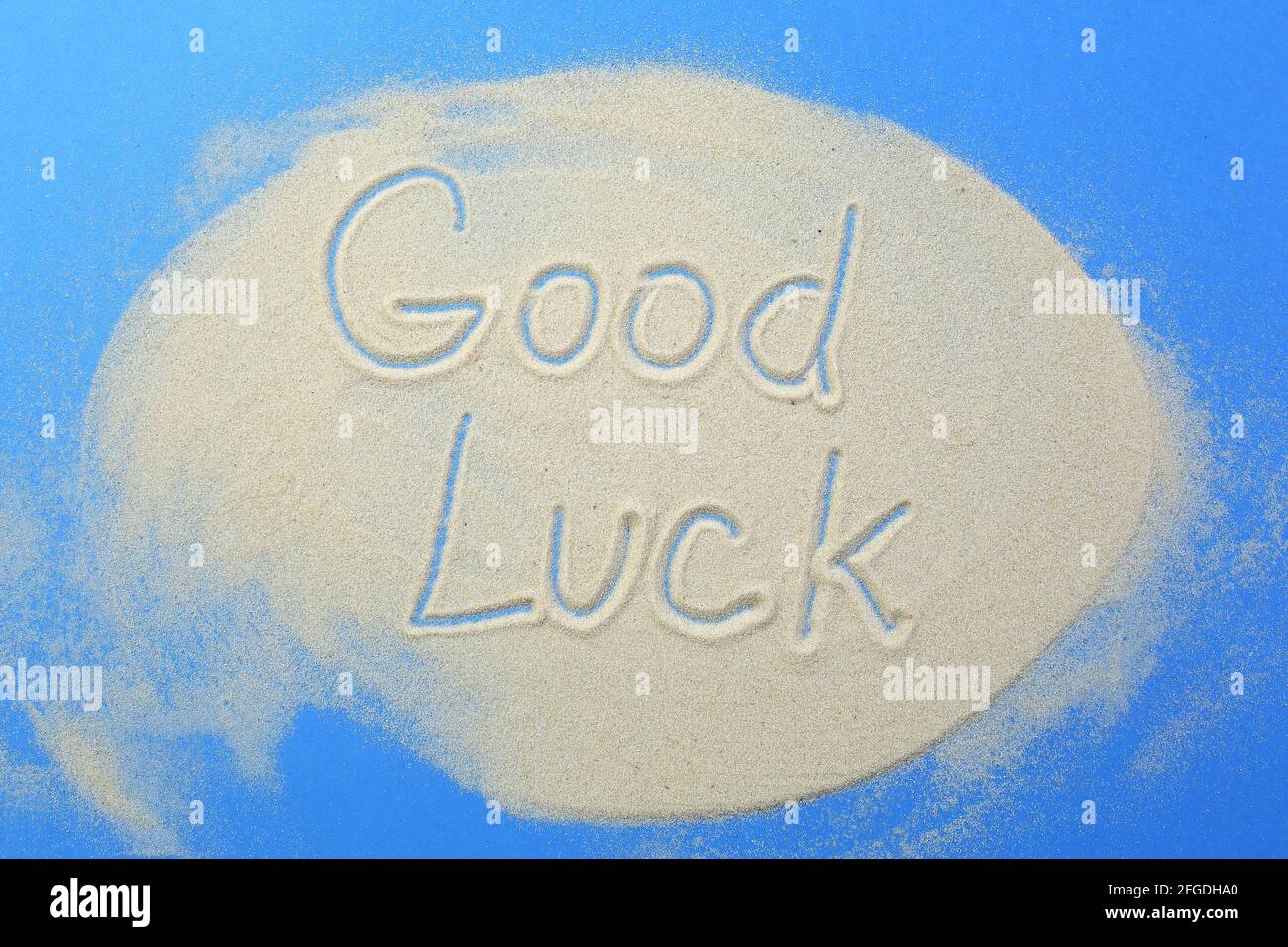 Les mots bonne chance sont écrits dans le sable sur fond bleu. Banque D'Images