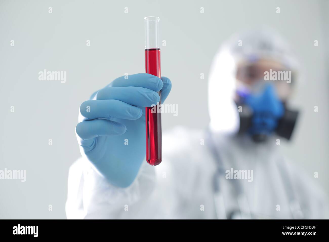 Un homme en costume de protection tient un tube à essai dans ses mains. Le concept de vaccins ouverts contre le coronavirus Banque D'Images