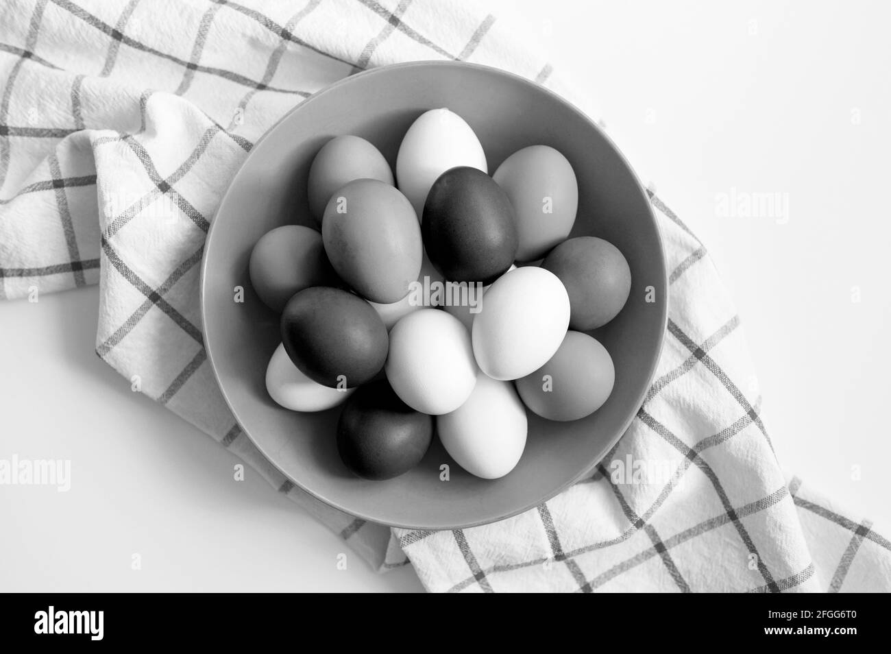 œufs de poulet de couleur blanche et noire dans une assiette une serviette de cuisine à carreaux sur une table blanche Banque D'Images