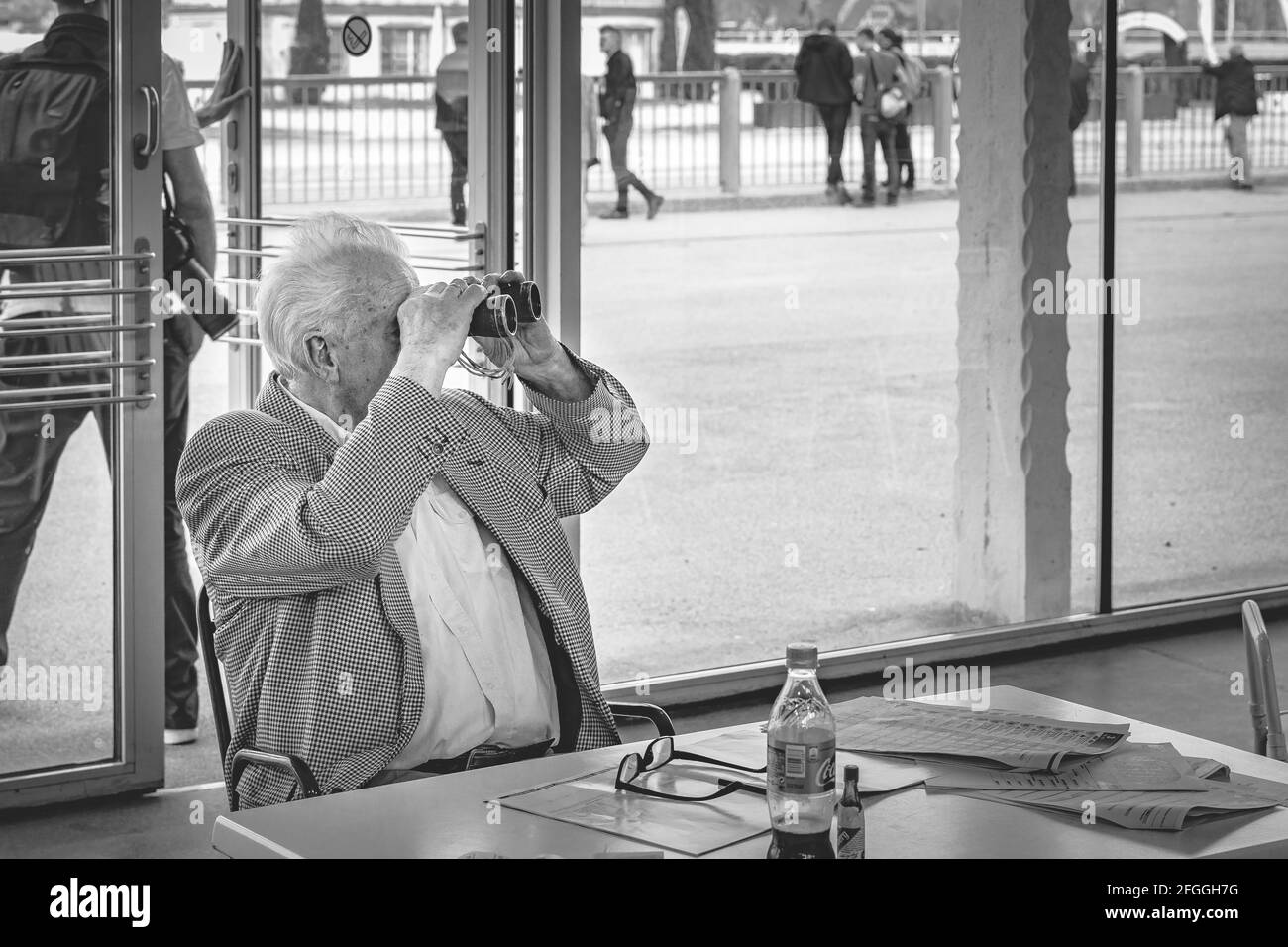 Un vieil homme regarde à travers des jumelles, en noir et blanc, sans mise en scène Banque D'Images