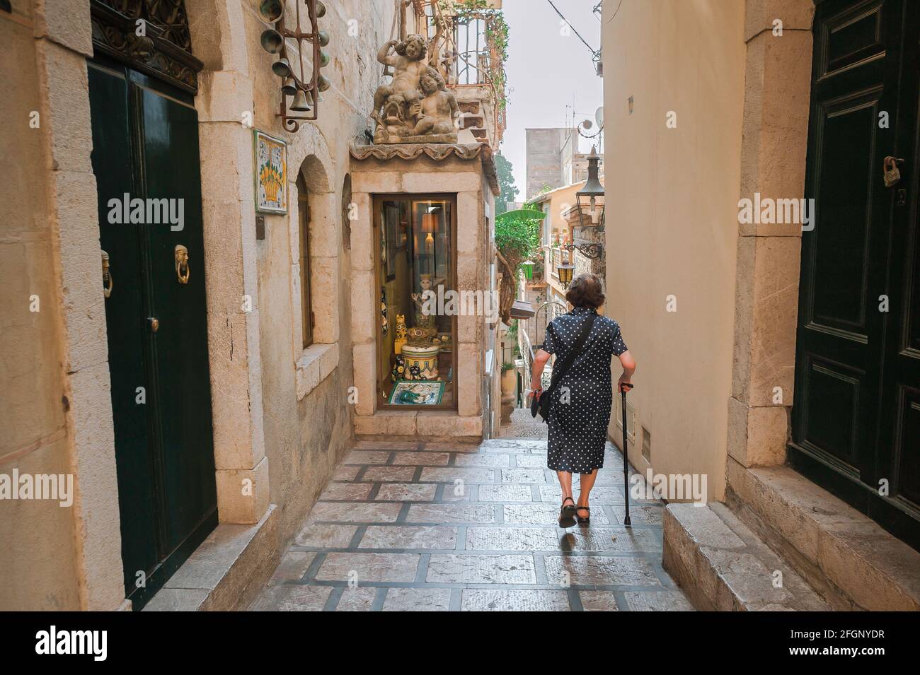Femme âgée marchant, vue arrière d'une femme sicilienne âgée avec un bâton de marche dans une rue de Taormina, Sicile. Banque D'Images