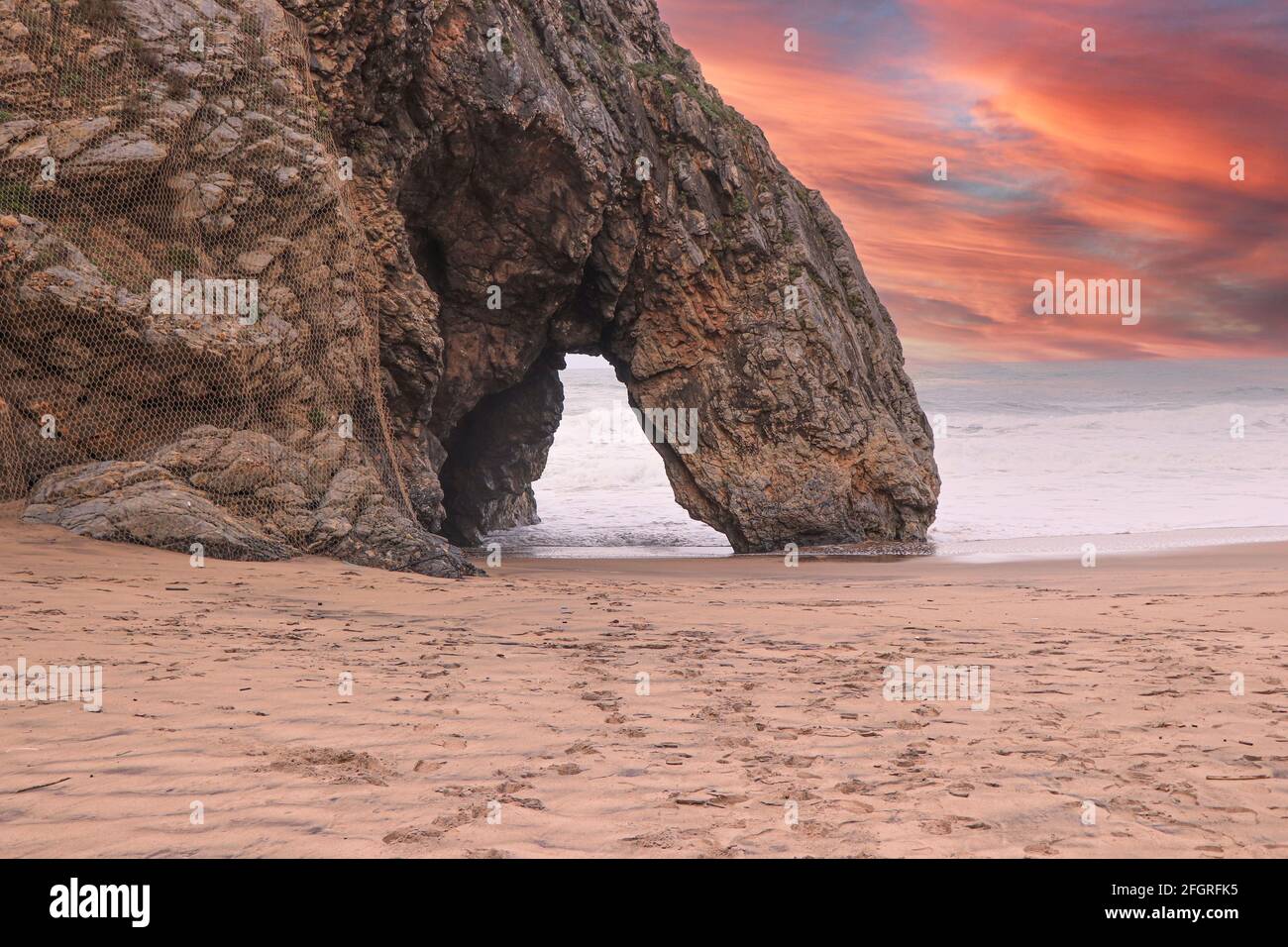 Belle pierre naturelle arche au coucher du soleil. Formation de roches dans une plage avec l'océan en arrière-plan. Banque D'Images