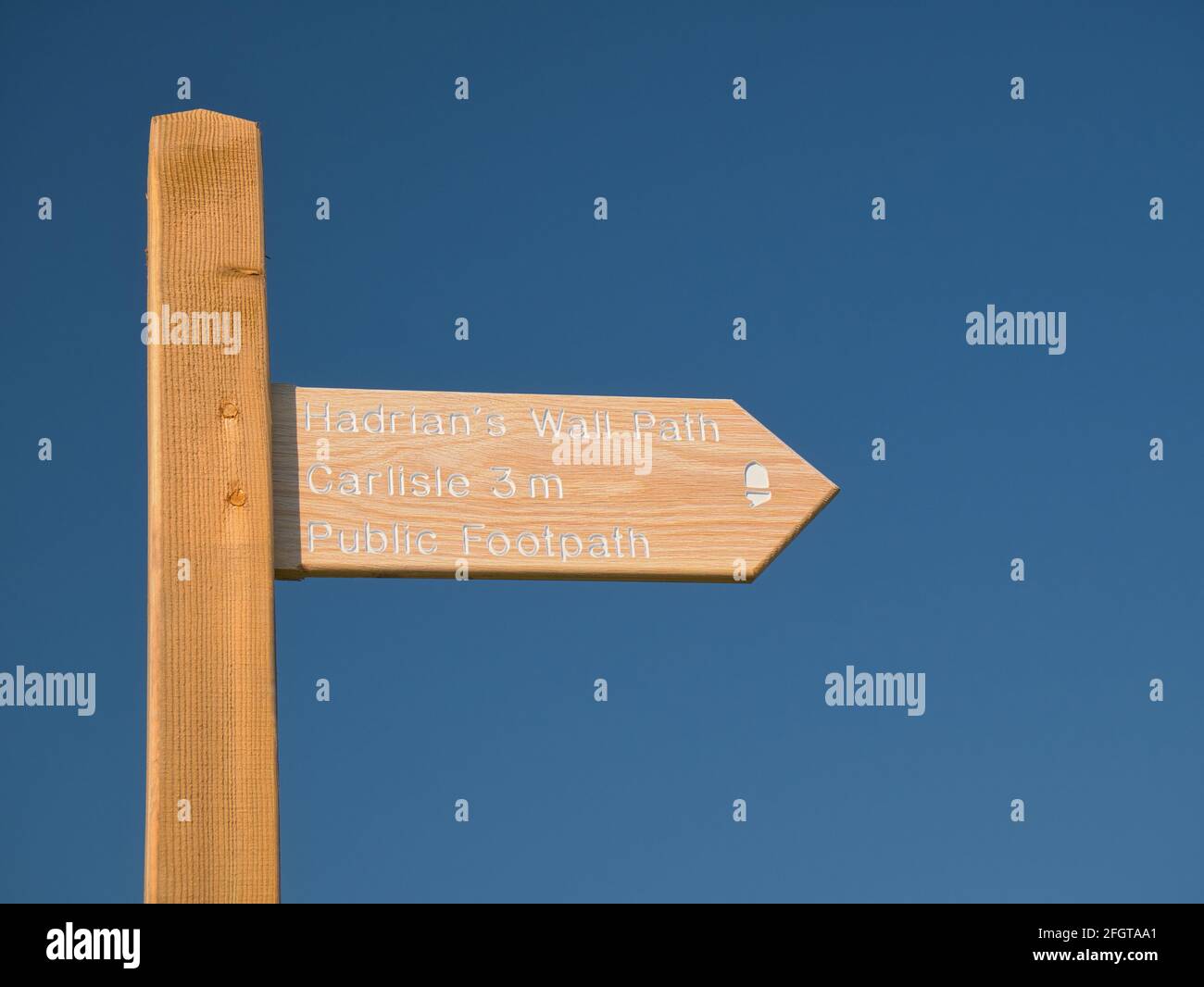 Un nouveau panneau en bois sur le chemin du mur d'Hadrien sur la côte de Solway, Cumbria, Royaume-Uni, à 3 miles de Carlisle, isolé contre un ciel bleu clair sans c Banque D'Images