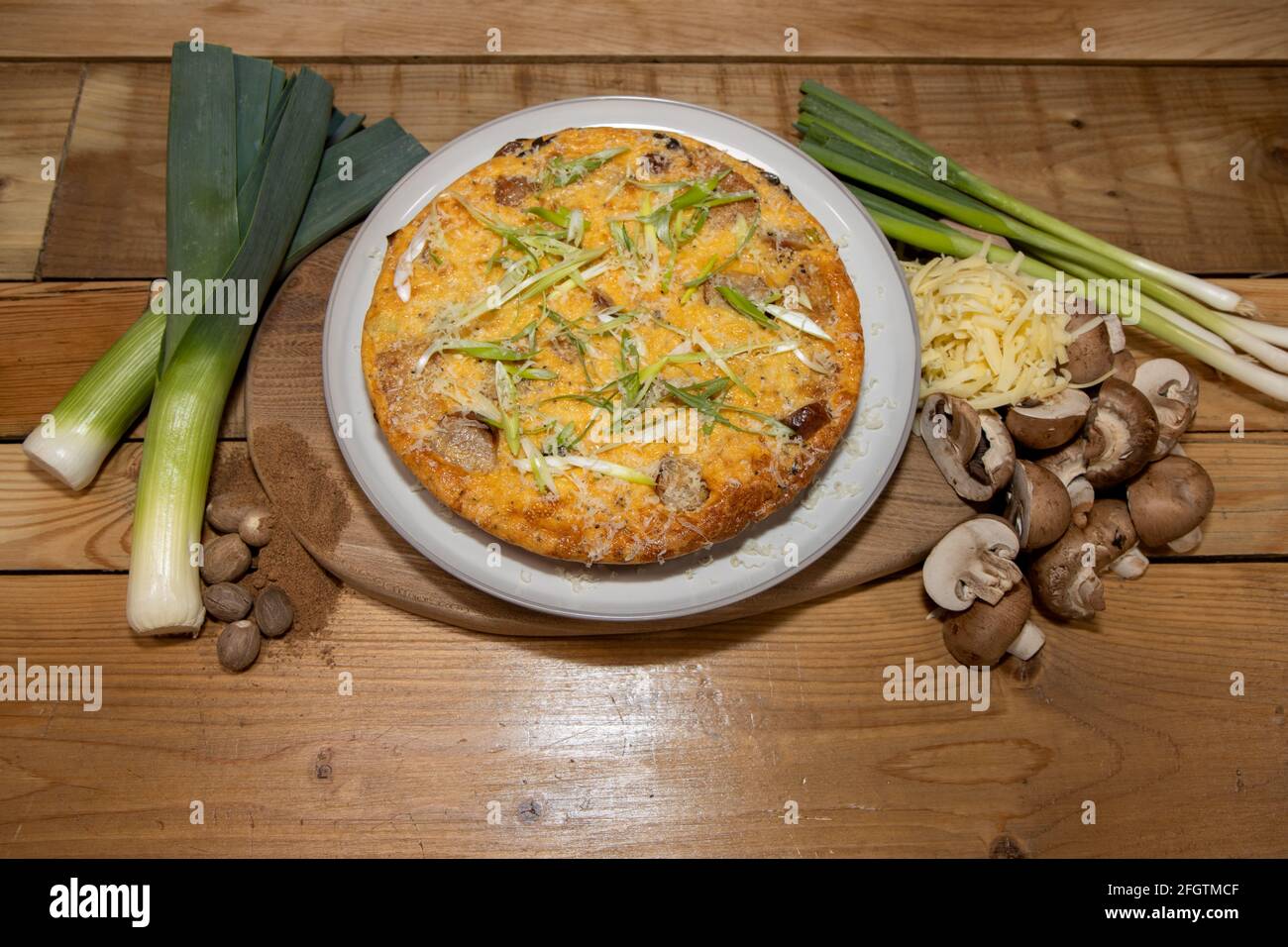 Une délicieuse saucisse cuite et Hash Brown Frittata entouré les ingrédients utilisés pour cuire le plat sur un bois table de cuisine Banque D'Images