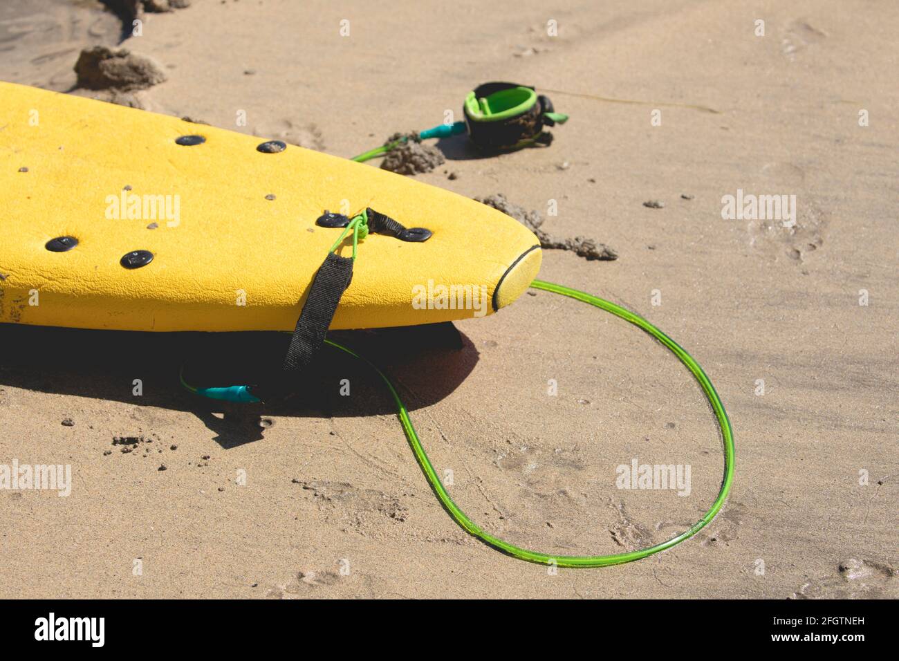 Surf de couleur jaune avec la laisse, reposant sur le sable près de la rive après une leçon de surf sur la plage de San Antonio, Espasante, dans le pays Banque D'Images