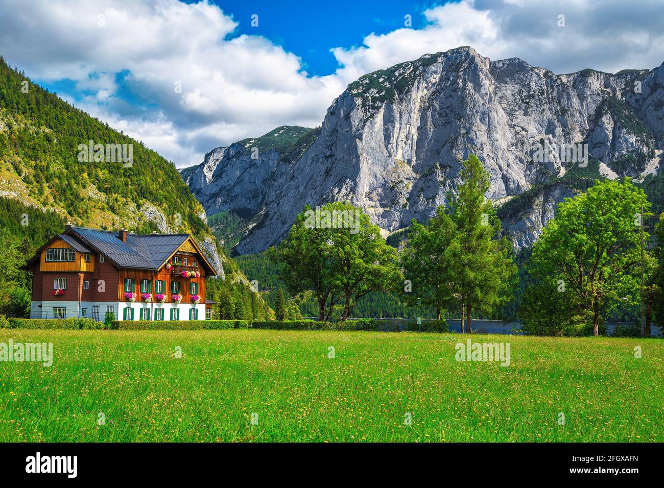 Jolie maison en bois alpin avec des champs verts et de hautes falaises en arrière-plan, lac Altaussee, Autriche, Europe Banque D'Images