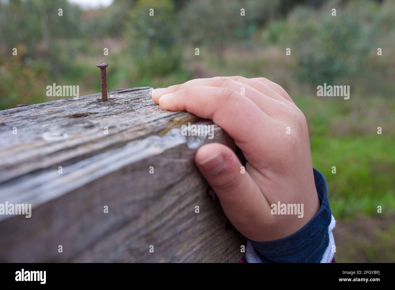 Enfant garçon main saisir une planche avec l'ongle rouillé près. Mise au point sélective Banque D'Images