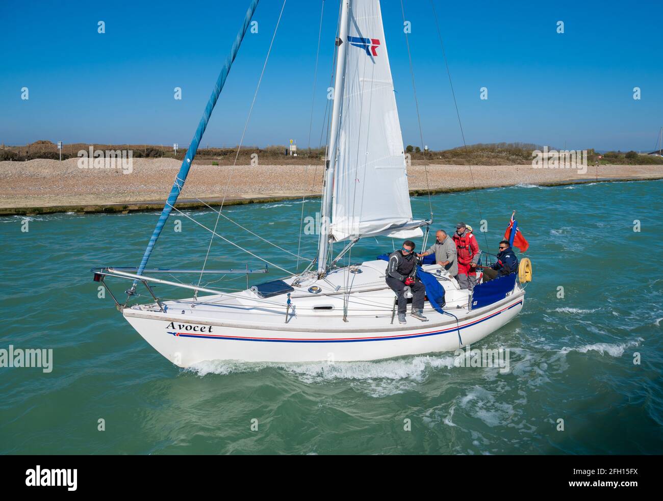 Groupe de personnes en voyage de voile sur un petit yacht, en train de remonter l'estuaire de la rivière Arun au printemps à Littlehampton, West Sussex, Angleterre, Royaume-Uni. Banque D'Images