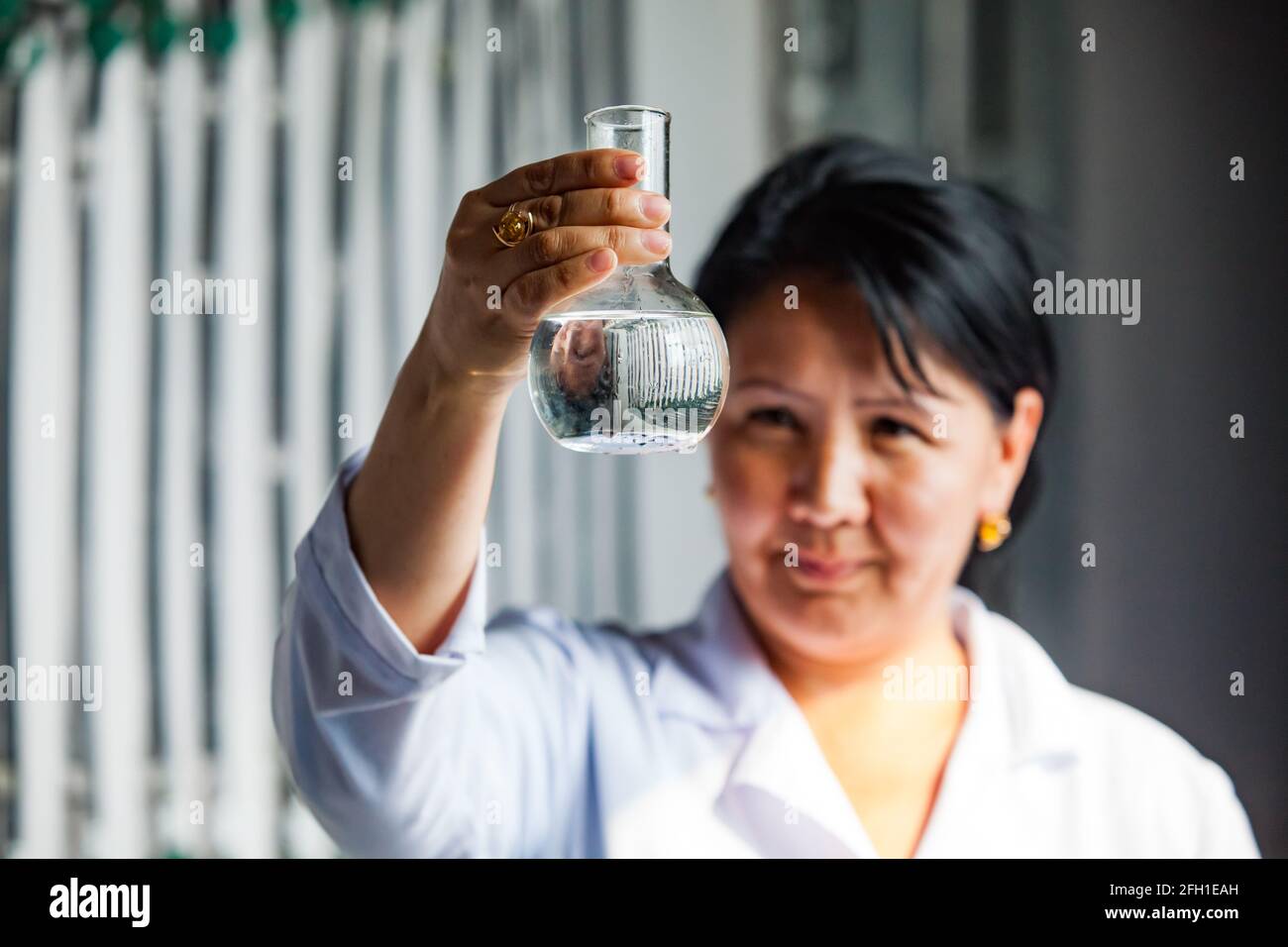 Kyzylorda, Kazakhstan: Station de purification de l'eau. Le chimiste prélève des échantillons d'eau purifiée. Eau transparente dans le flacon (au foyer). La femme est floue. Banque D'Images