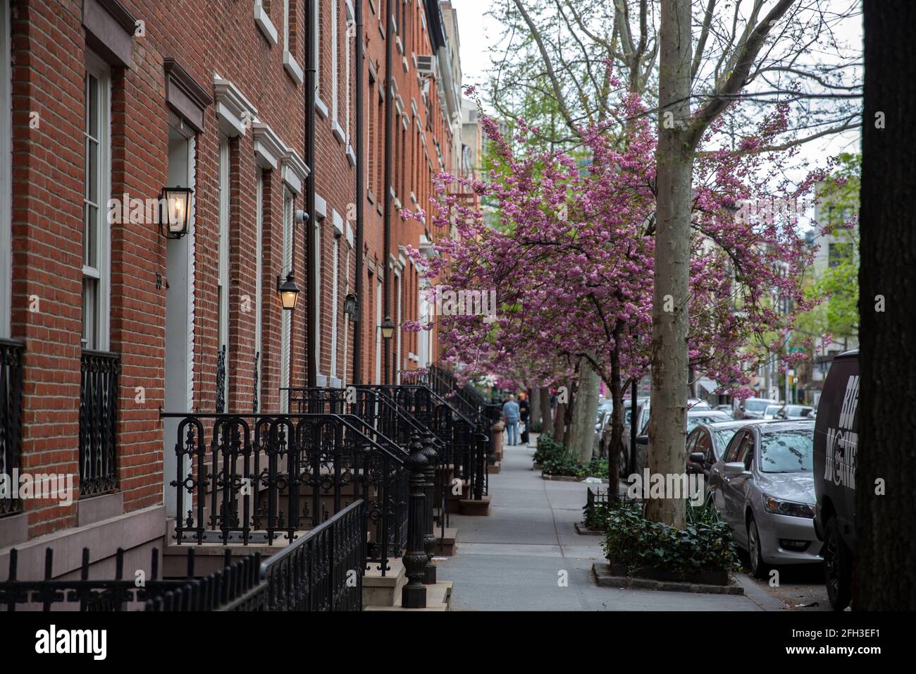 New York - 18 2021 avril : une rangée de bâtiments en grès brun avec lampe à gaz à chaque entrée de Manhattan, New York. Printemps avec arbre en fleurs dedans Banque D'Images