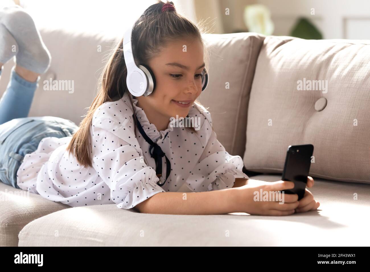 Bonne adolescente utiliser le téléphone cellulaire à la maison Banque D'Images