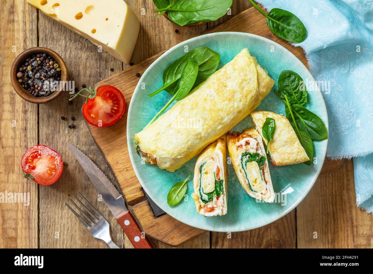 Cuisine japonaise. Plat national japonais omelette tamago yaki pour le petit-déjeuner. Œuf roulé aux épinards, à la tomate et au fromage sur une table en bois. Vue de dessus, Fla Banque D'Images