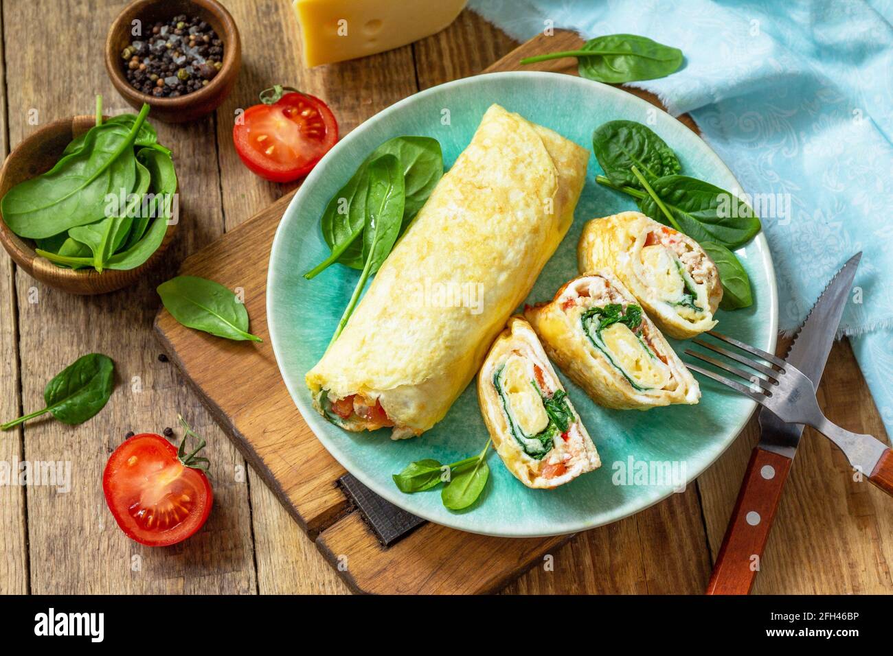 Cuisine japonaise. Plat national japonais omelette tamago yaki pour le petit-déjeuner. Œuf roulé aux épinards, à la tomate et au fromage sur une table en bois. Banque D'Images
