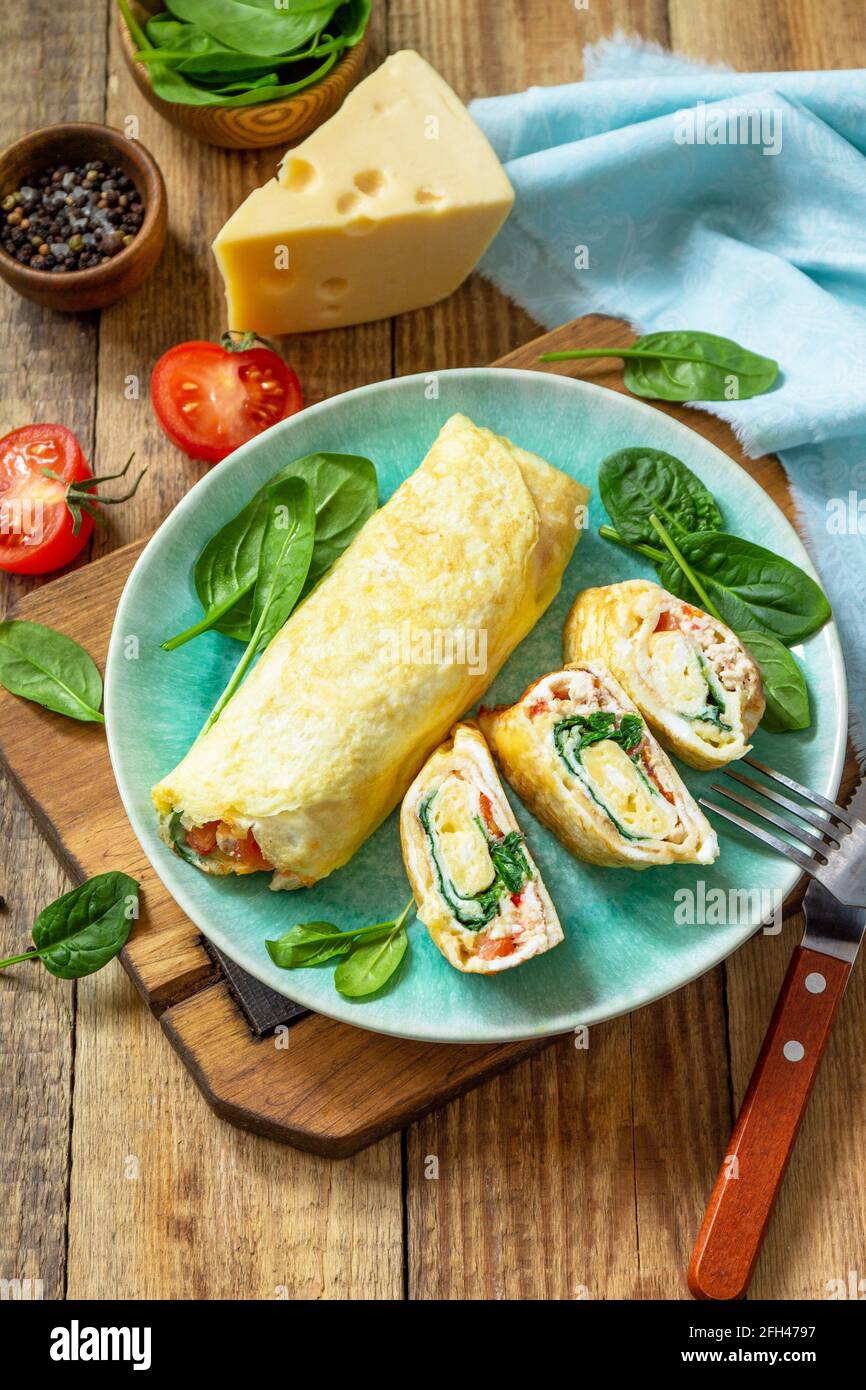 Cuisine japonaise. Plat national japonais omelette tamago yaki pour le petit-déjeuner. Œuf roulé aux épinards, à la tomate et au fromage sur une table en bois. Copier l'espace. Banque D'Images