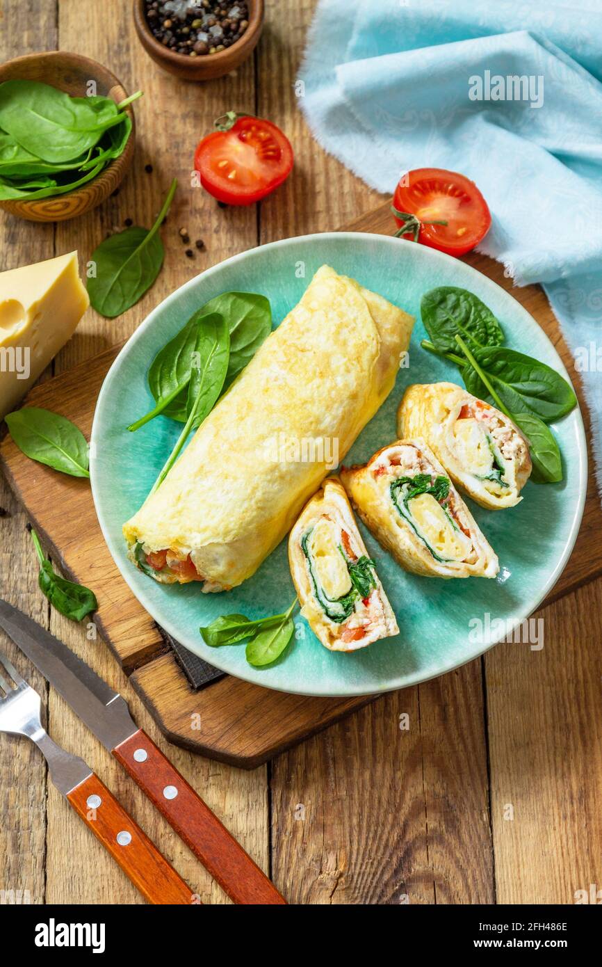 Cuisine japonaise. Plat national japonais omelette tamago yaki pour le petit-déjeuner. Œuf roulé aux épinards, à la tomate et au fromage sur une table en bois. Copier l'espace. Banque D'Images