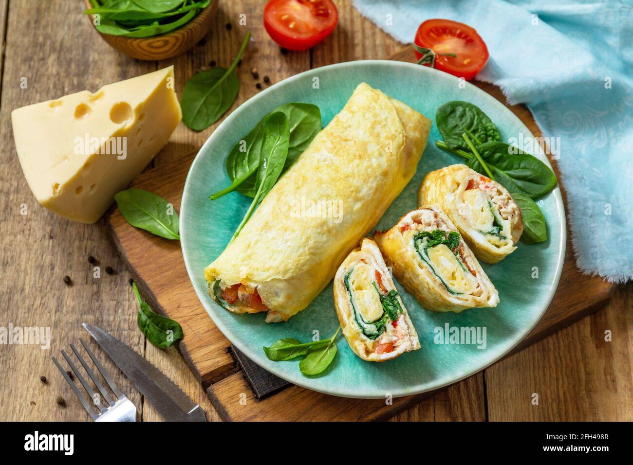 Cuisine japonaise. Plat national japonais omelette tamago yaki pour le petit-déjeuner. Œuf roulé aux épinards, à la tomate et au fromage sur une table en bois. Banque D'Images