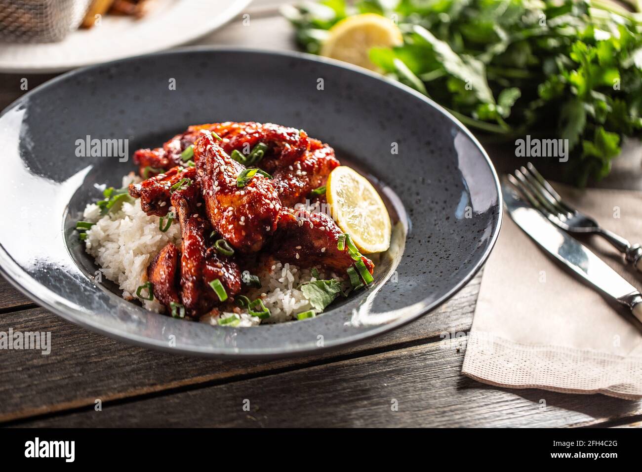Poulet glacé au miel de style asiatique, feuilles de coriandre, riz et citron. Banque D'Images