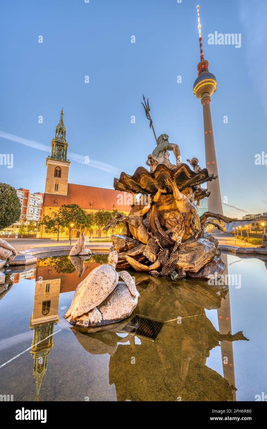La fontaine Neptune à Alexanderplatz à Berlin au lever du soleil avec Le célèbre Fernsehturm et le Marienkirche Banque D'Images