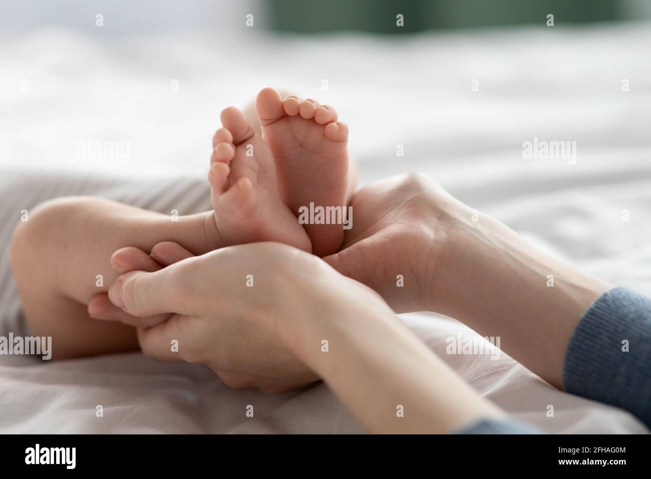 Soins aux mères. Gros plan de maman aimante tenant les pieds du nouveau-né dans les mains Banque D'Images