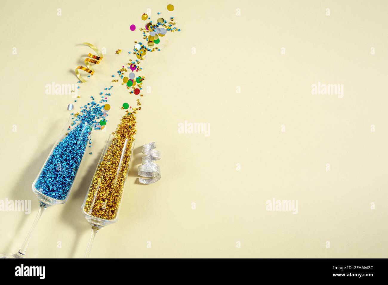 Paire de verres à vin de fête avec scintillant, confetti et sur fond crème, vue du dessus. Plat inspiration Party Banque D'Images