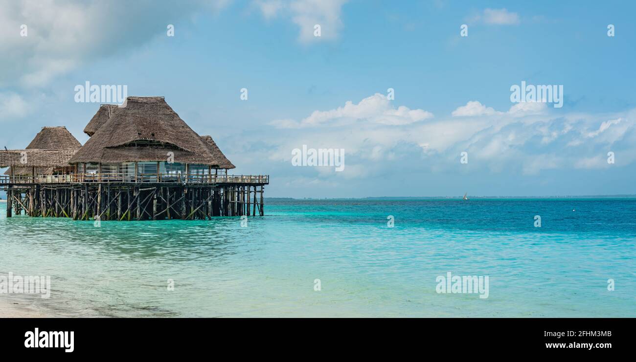 ZANZIBAR, TANZANIE - 12 FÉVRIER 2020 : Plage tropicale blanche de l'île de Zanzibar avec un toit de chaume sur l'eau Banque D'Images