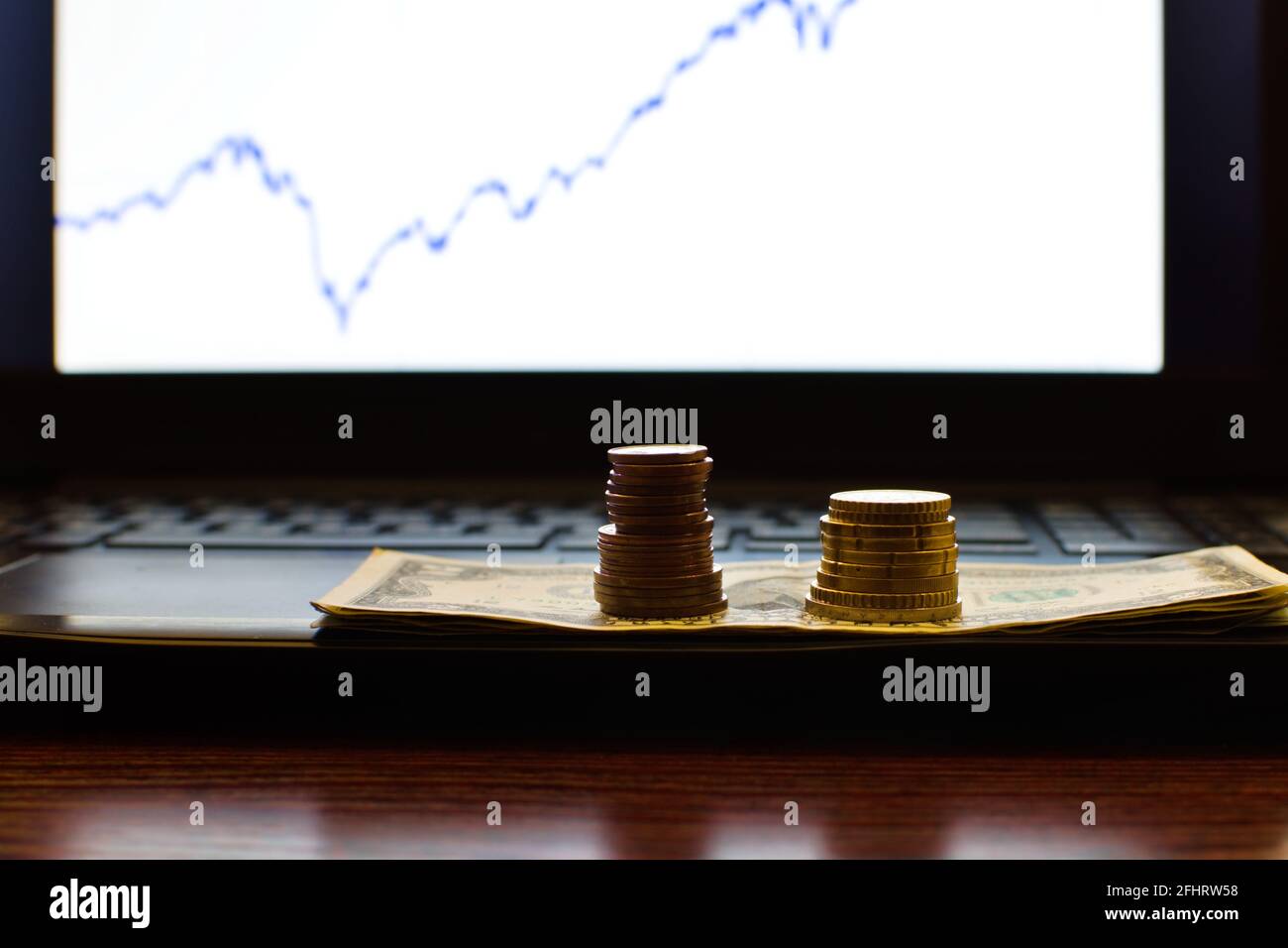 piles de pièces sur un arrière-plan d'écran d'ordinateur flou avec du stock graphique Banque D'Images