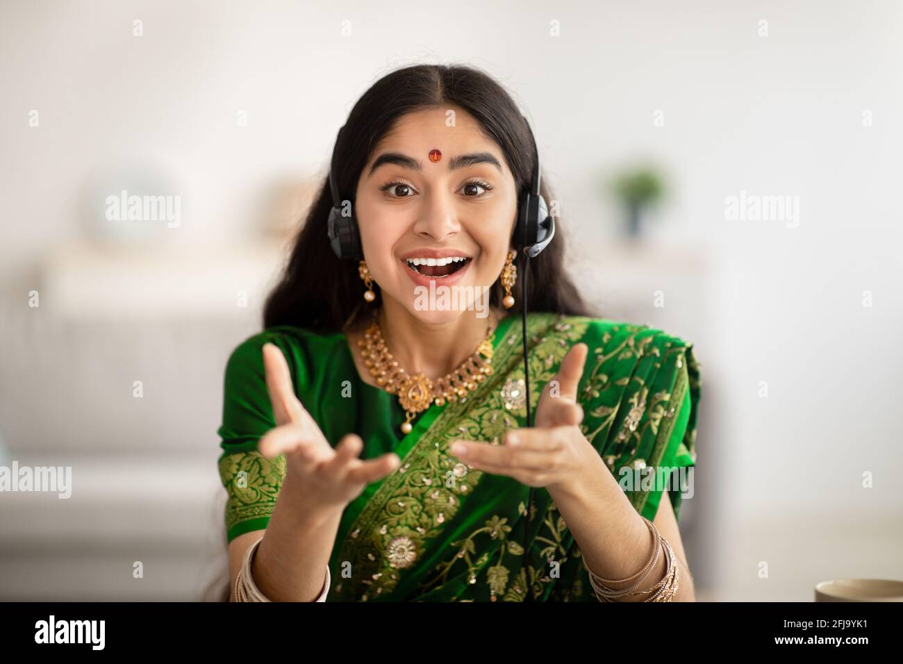 Vue portrait d'une femme indienne gaie en robe de sari passer un appel vidéo, en utilisant l'ordinateur de la maison Banque D'Images