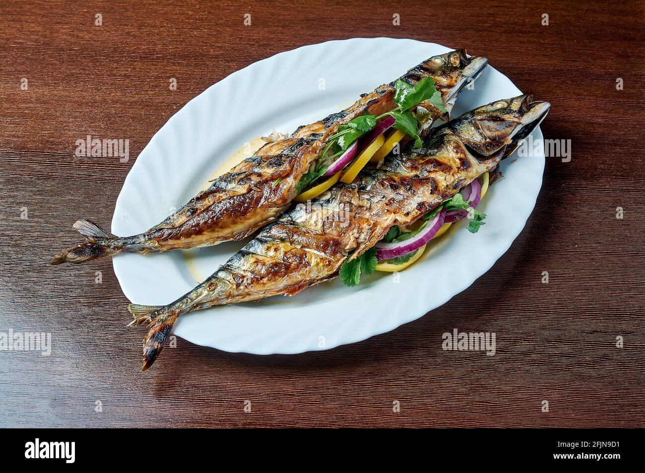 Le maquereau cuit sur le gril repose sur une assiette blanche Banque D'Images