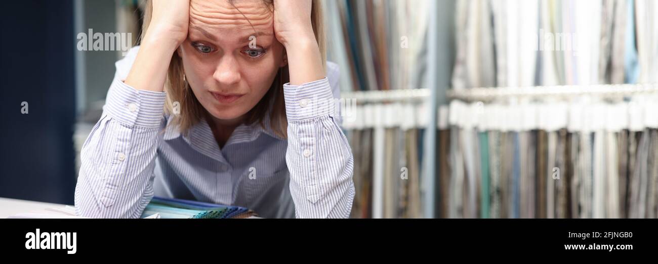 Une femme confuse choisit des tissus dans le magasin Banque D'Images