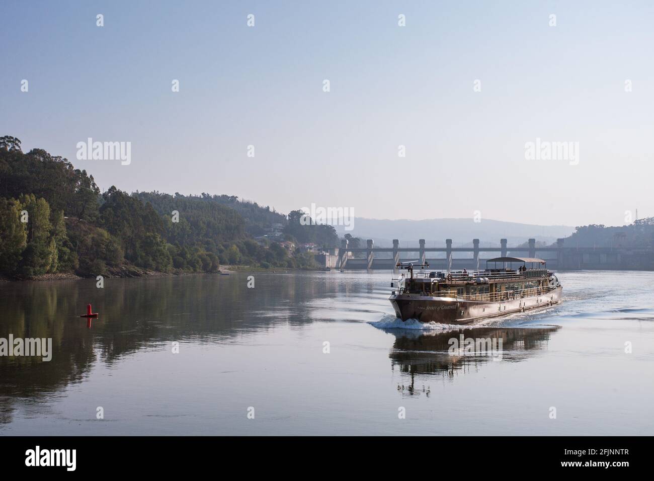 Un bateau naviguant dans la vallée du Douro, dans le nord du Portugal, avec le barrage de Crestuma-lever en arrière-plan. Banque D'Images