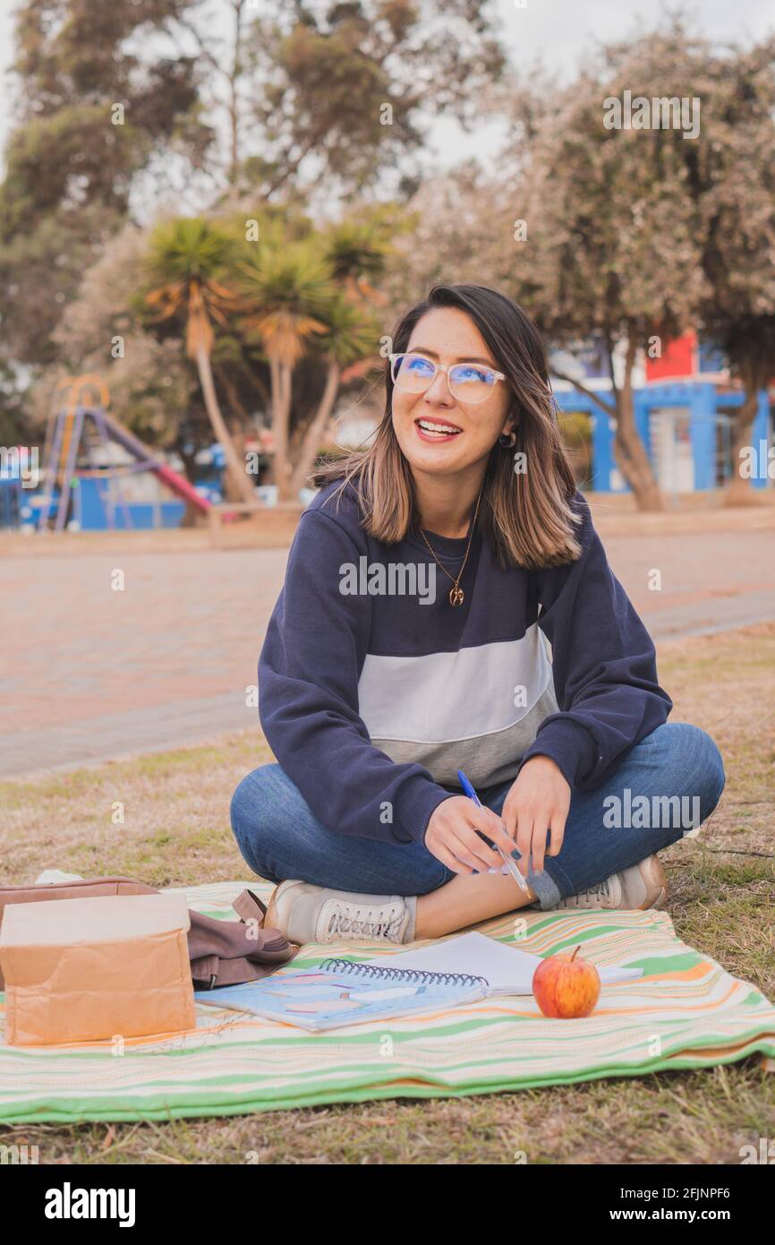 Jeune étudiant étudiant dans le parc, prenant des notes et apprenant tout sur ses sujets. Banque D'Images