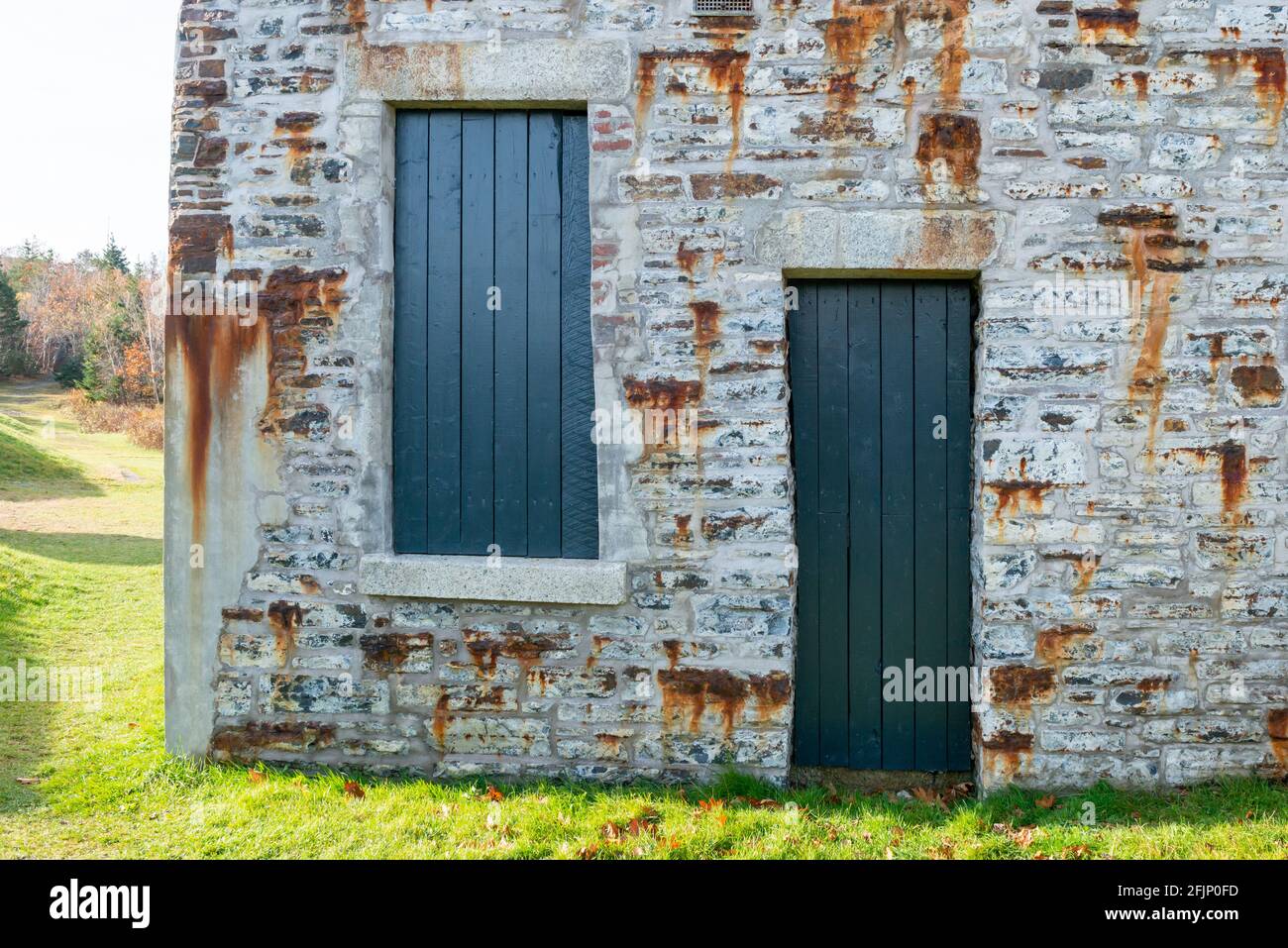 Une porte en bois d'époque bleu vif avec une petite ouverture de fenêtre sur le dessus. L'entrée est dans un vieux mur de roche rustique texturé. Banque D'Images
